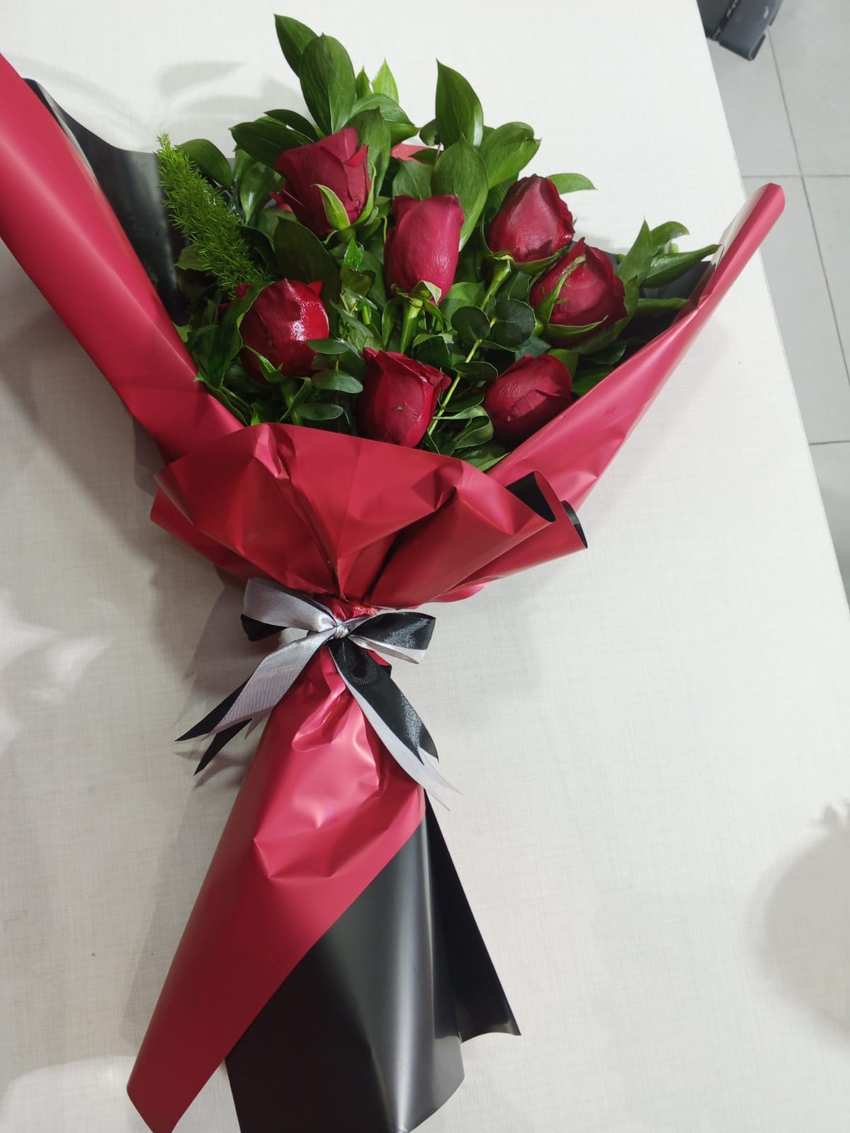 Six red roses with eucalyptus in red and black wrapper with silver bow